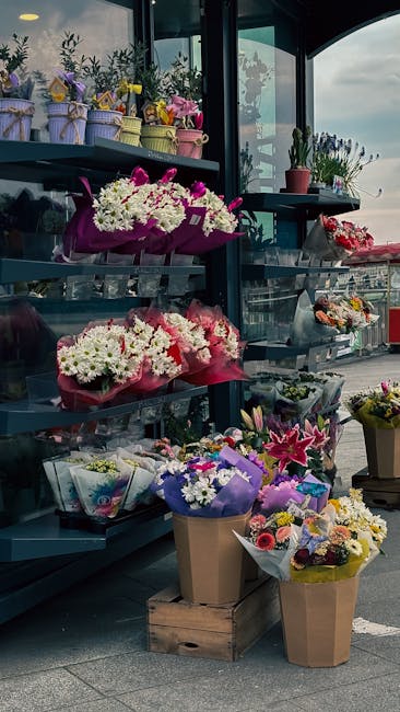 A display of various floral arrangements and bouquets at Friern Barnet Flowers, showcasing vibrant colors and diverse flower types such as white chrysanthemums, pink lilies, and purple irises. The flo