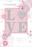 In this image, an anniversary card is displayed as though just lifted from a gift bag on a quiet Friern Barnet evening, its design capturing the intimacy of a shared celebration at home. The card's centre showcases the word 'LOVE' in large, raised letters, each coated in a soft, glittery finish that shifts between blush pink and silvery-white as the light moves across it, much like dew on the petals of freshly delivered roses. The letterforms are full and inviting, encouraging fingers to trace their textured surface. Encircling this focal word is a delicate constellation of illustrated blossoms and flowing vines, drawn with hair-fine lines that arc and loop as gracefully as trailing foliage in a carefully arranged anniversary bouquet. The colour story remains quietly romantic: pastel pinks, muted mauves, pearlescent whites, and hints of silver that echo the dignified calm of Friern Barnet's tree-lined streets. The background holds a soft pink wash, smooth and velvety, allowing the floral details and glittering word to stand out without harsh edges. Small flourishes-tiny petals, curled tendrils, and discreet butterfly motifs-add a sense of movement, as if a gentle breeze were passing through an English spring garden. Elegant script writing appears around and beneath the central design, spelling out anniversary wishes and reaffirming lasting love with restraint rather than grand gestures. The overall impression is of a thoughtful keepsake, the sort of card one might send alongside a hand-tied arrangement delivered across N11: quiet, refined, and deeply personal, capturing the feeling of love that has grown steadily, season after season.
